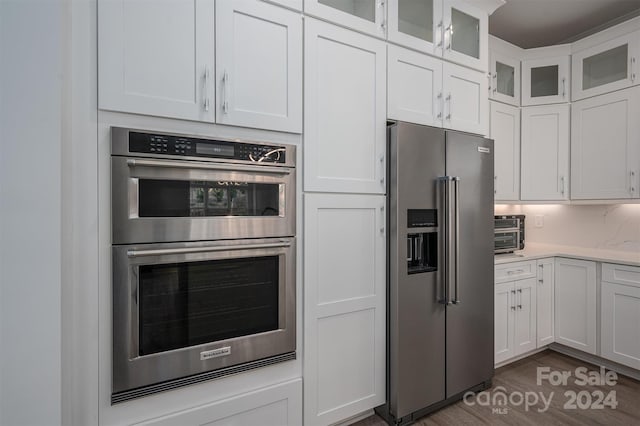 kitchen with white cabinetry, appliances with stainless steel finishes, and dark hardwood / wood-style flooring