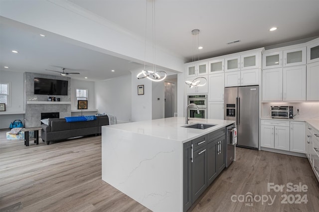 kitchen featuring sink, white cabinetry, decorative light fixtures, a center island with sink, and stainless steel appliances