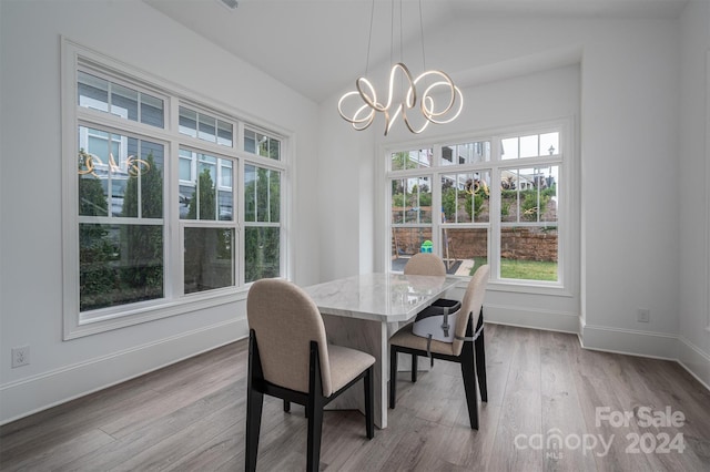 dining room featuring an inviting chandelier, vaulted ceiling, and light hardwood / wood-style flooring