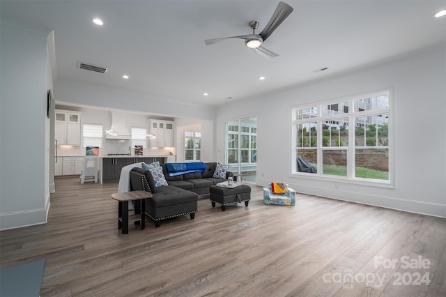 living room with ceiling fan, crown molding, and light hardwood / wood-style floors