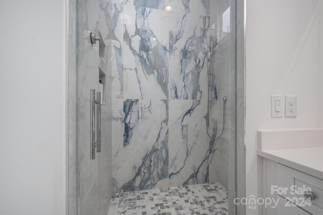 bathroom with tiled shower and vanity