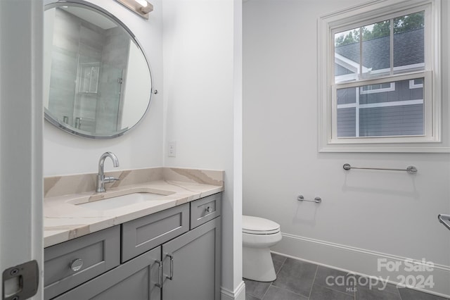 bathroom featuring tile patterned flooring, vanity, walk in shower, and toilet