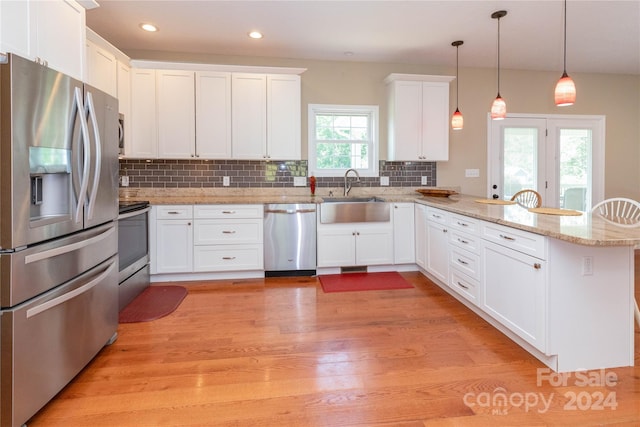 kitchen featuring white cabinetry, sink, stainless steel appliances, kitchen peninsula, and decorative light fixtures