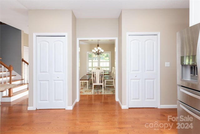 interior space featuring light hardwood / wood-style floors, stainless steel refrigerator with ice dispenser, hanging light fixtures, and a chandelier