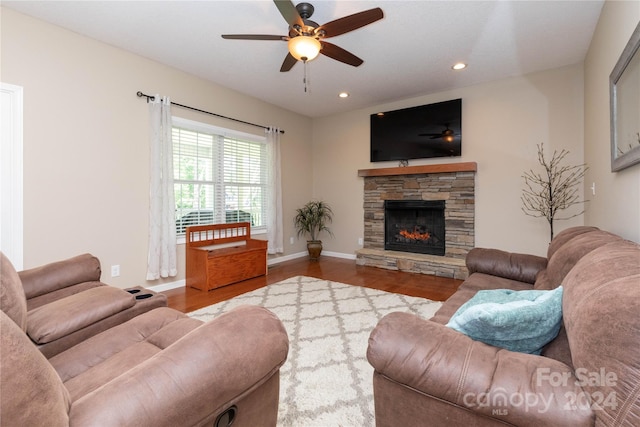 living room with hardwood / wood-style floors, ceiling fan, and a stone fireplace