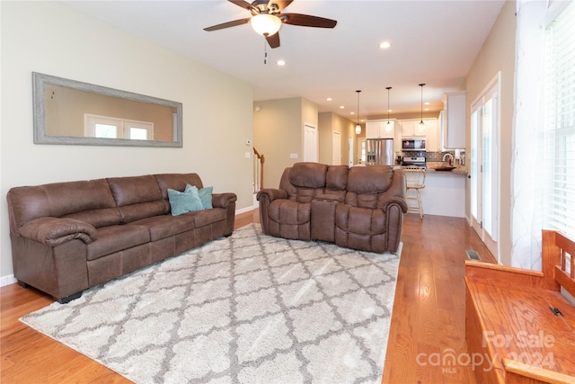 living room featuring ceiling fan, sink, and light hardwood / wood-style flooring