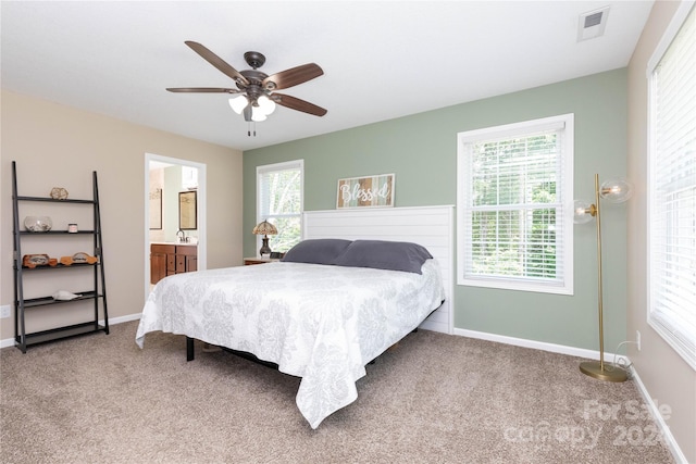 carpeted bedroom with ceiling fan, sink, connected bathroom, and multiple windows