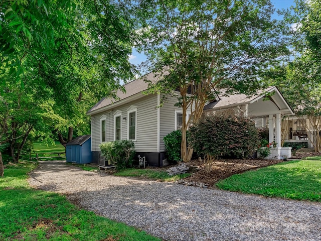 view of home's exterior with a lawn and a storage unit