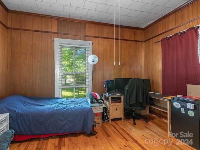 bedroom featuring crown molding, wood walls, and light wood-type flooring