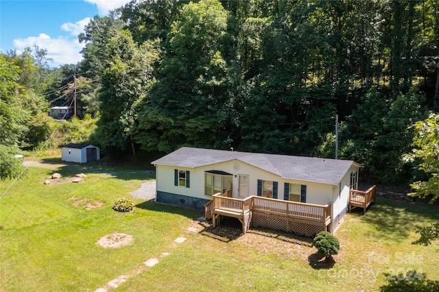 view of front facade with a front yard, a deck, and a storage shed