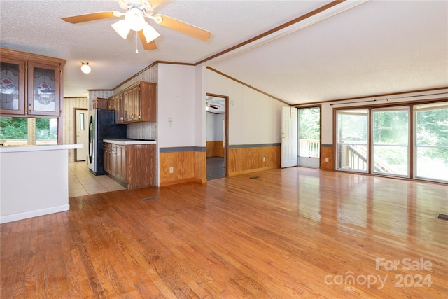 kitchen with vaulted ceiling, stainless steel refrigerator, ceiling fan, crown molding, and light hardwood / wood-style flooring