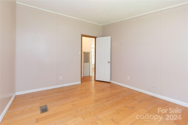 empty room featuring crown molding, hardwood / wood-style floors, and a textured ceiling