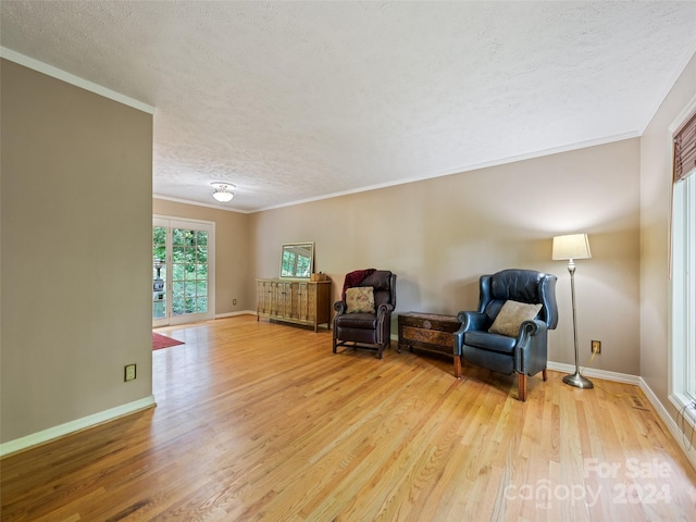 living area with a textured ceiling, light wood-type flooring, and ornamental molding