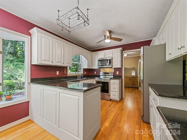 kitchen featuring white cabinetry, light hardwood / wood-style flooring, ceiling fan, and stainless steel appliances