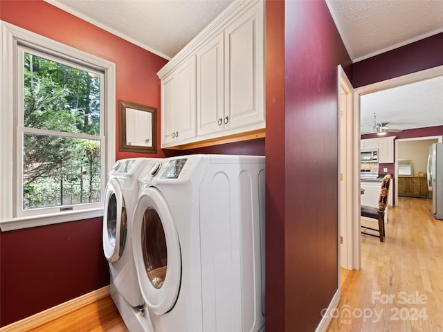 laundry room featuring washing machine and dryer, light hardwood / wood-style flooring, cabinets, and a textured ceiling