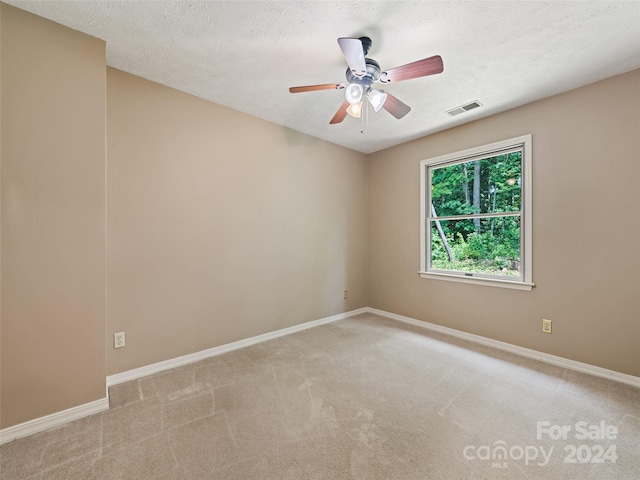 empty room featuring light carpet, ceiling fan, and a textured ceiling