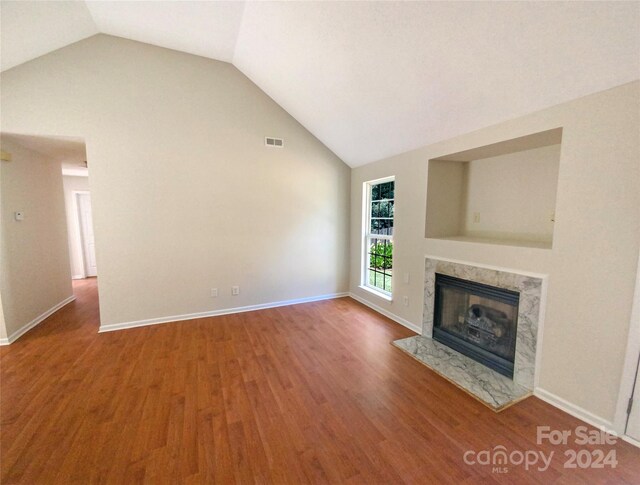 unfurnished living room with a fireplace, vaulted ceiling, and hardwood / wood-style floors