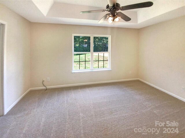 carpeted empty room featuring ceiling fan and a tray ceiling