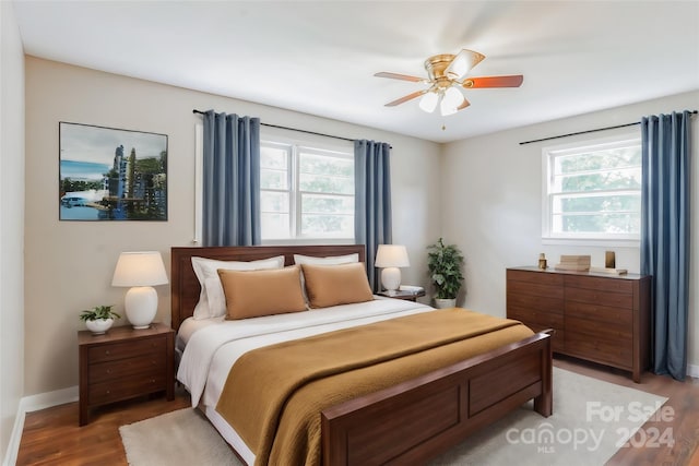 bedroom with ceiling fan, multiple windows, and wood-type flooring