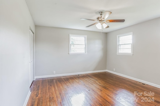 spare room featuring ceiling fan, a healthy amount of sunlight, and dark wood-type flooring