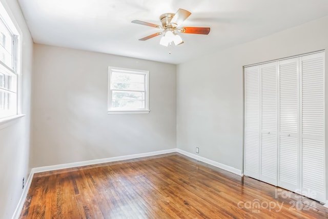 unfurnished bedroom with ceiling fan, a closet, and hardwood / wood-style flooring