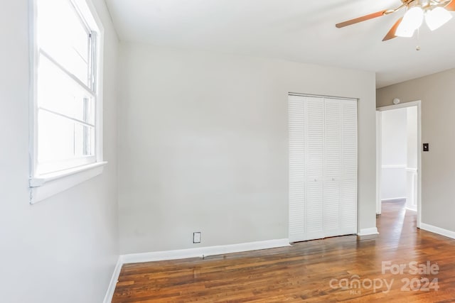 unfurnished bedroom with dark wood-type flooring, ceiling fan, and a closet