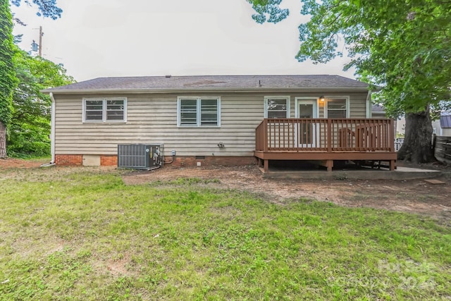 rear view of house featuring a wooden deck, cooling unit, and a lawn