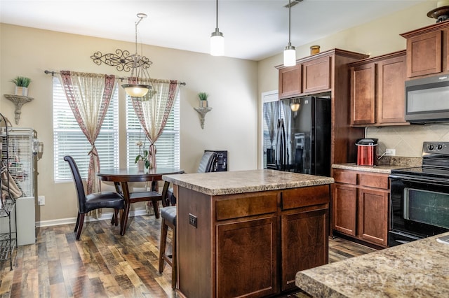 kitchen with decorative light fixtures, backsplash, dark hardwood / wood-style floors, a kitchen island, and black appliances