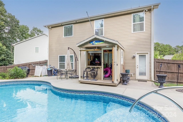 rear view of property featuring a patio area and a fenced in pool