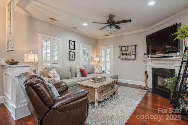 living room with crown molding, ceiling fan, and dark wood-type flooring