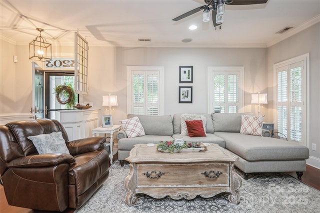 living room featuring ceiling fan with notable chandelier, hardwood / wood-style flooring, and ornamental molding