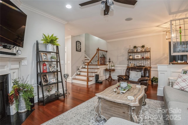 living room featuring a high end fireplace, ornamental molding, ceiling fan, and dark wood-type flooring