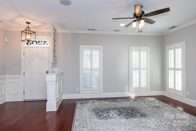 entryway featuring ceiling fan with notable chandelier, dark wood-type flooring, and ornamental molding