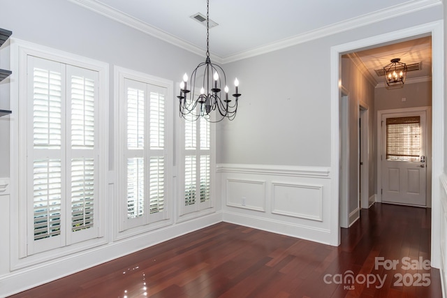 unfurnished dining area featuring crown molding, dark wood-type flooring, and a chandelier