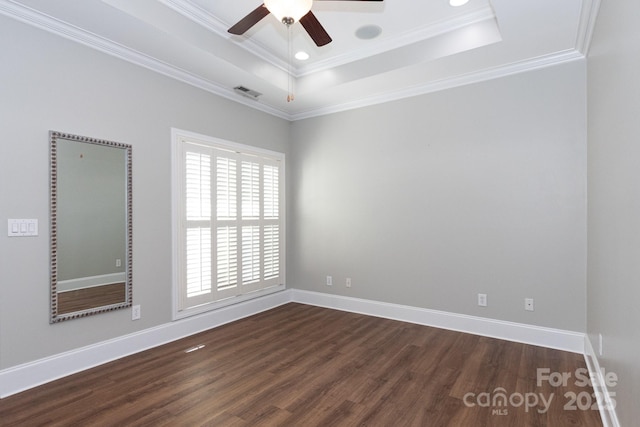 spare room with a raised ceiling, ornamental molding, and dark wood-type flooring