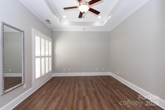 unfurnished room with a tray ceiling, crown molding, and dark wood-type flooring