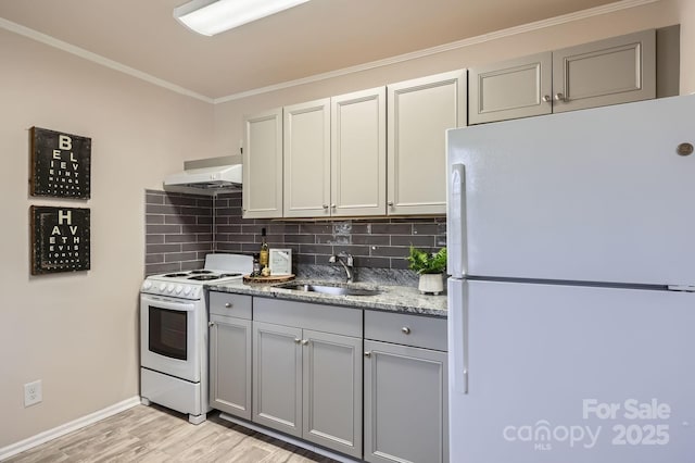 kitchen with white appliances, a sink, gray cabinetry, under cabinet range hood, and backsplash