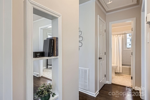 hall with dark wood-style flooring, visible vents, crown molding, and baseboards