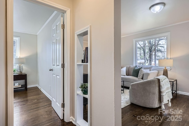 hallway with dark wood-type flooring, ornamental molding, and baseboards