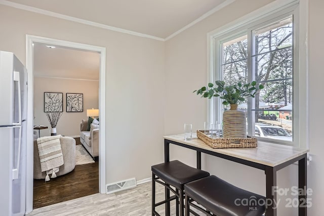 dining area featuring baseboards, ornamental molding, visible vents, and light wood-style floors