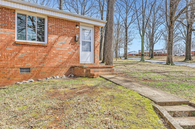 doorway to property featuring crawl space and brick siding