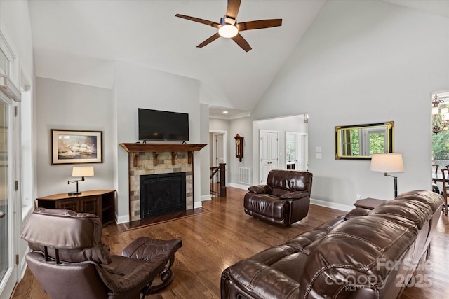 living area featuring a fireplace with flush hearth, a ceiling fan, baseboards, and wood finished floors