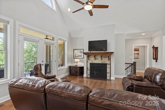 living area with french doors, a fireplace, wood finished floors, high vaulted ceiling, and baseboards