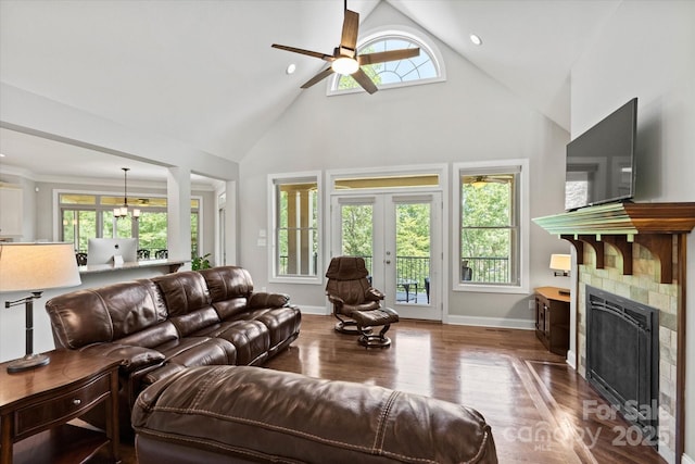 living room with baseboards, a tiled fireplace, wood finished floors, french doors, and high vaulted ceiling