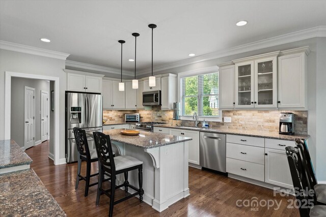 kitchen with a breakfast bar area, appliances with stainless steel finishes, dark wood-type flooring, and a sink