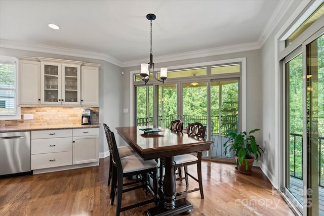 dining room featuring baseboards, ornamental molding, dark wood finished floors, and a chandelier