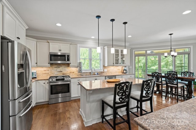 kitchen featuring white cabinets, ornamental molding, stainless steel appliances, and decorative backsplash