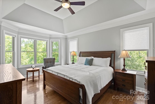 bedroom featuring wood finished floors, a ceiling fan, baseboards, ornamental molding, and a raised ceiling