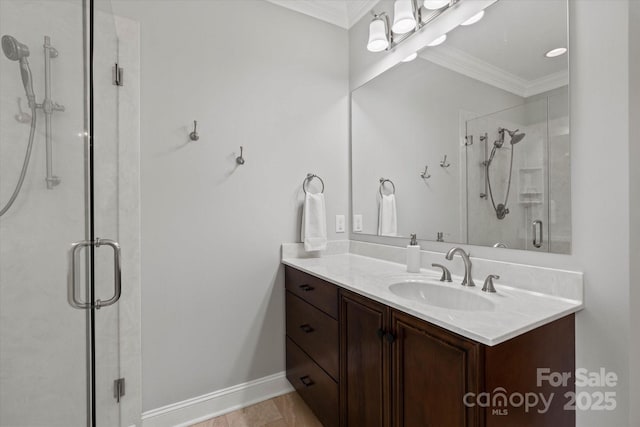 bathroom with baseboards, a stall shower, vanity, and crown molding