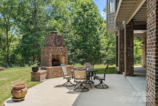 view of patio featuring an outdoor brick fireplace, outdoor dining space, and fence